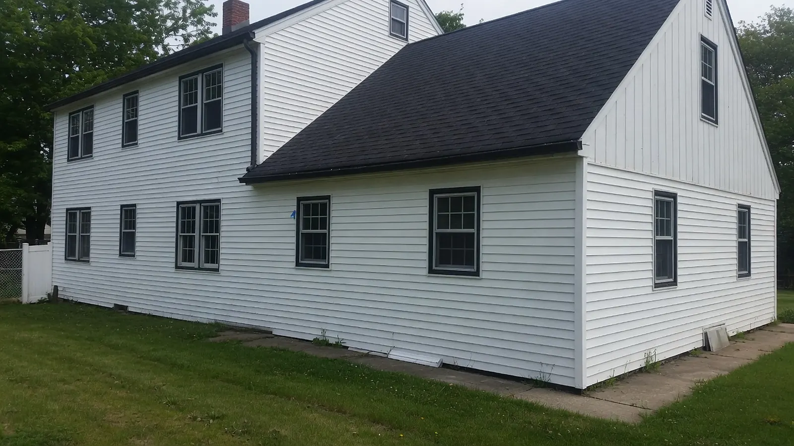 White house with horizontal lap siding on the walls and vertical board and batten siding on the gable end
