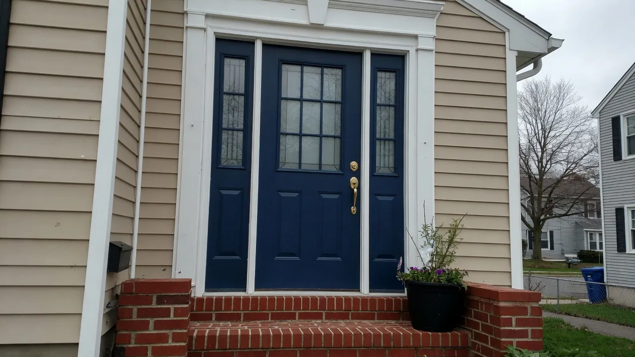 Navy blue fiberglass front door with a half-lite glass panel and two sidelights on a tan-sided house with brick steps