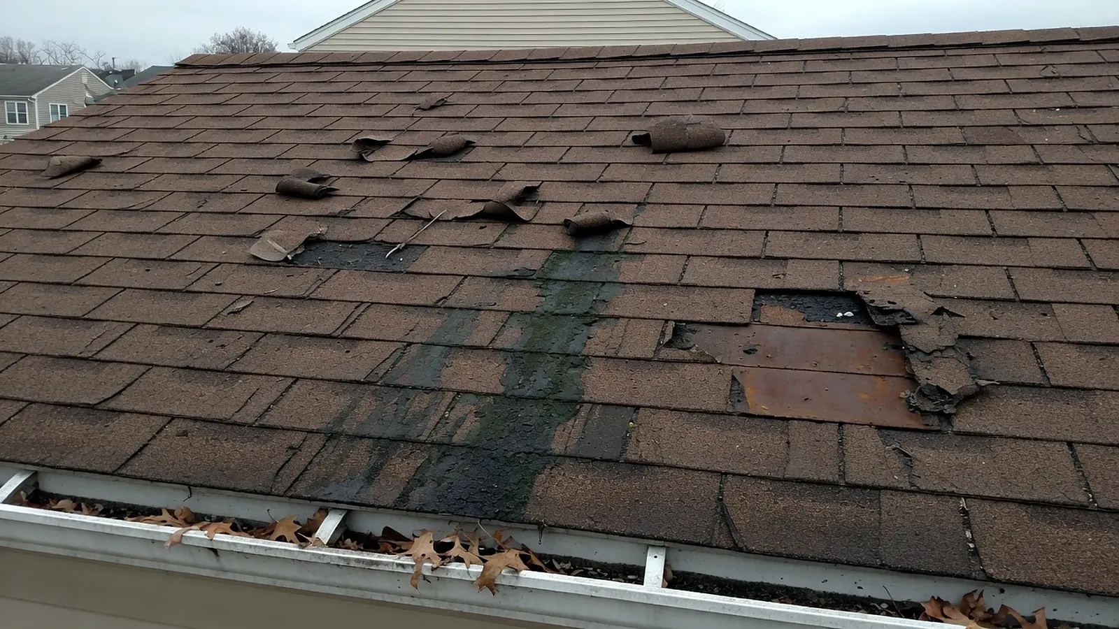 Close view of an aging shingle roof showing worn and missing shingles