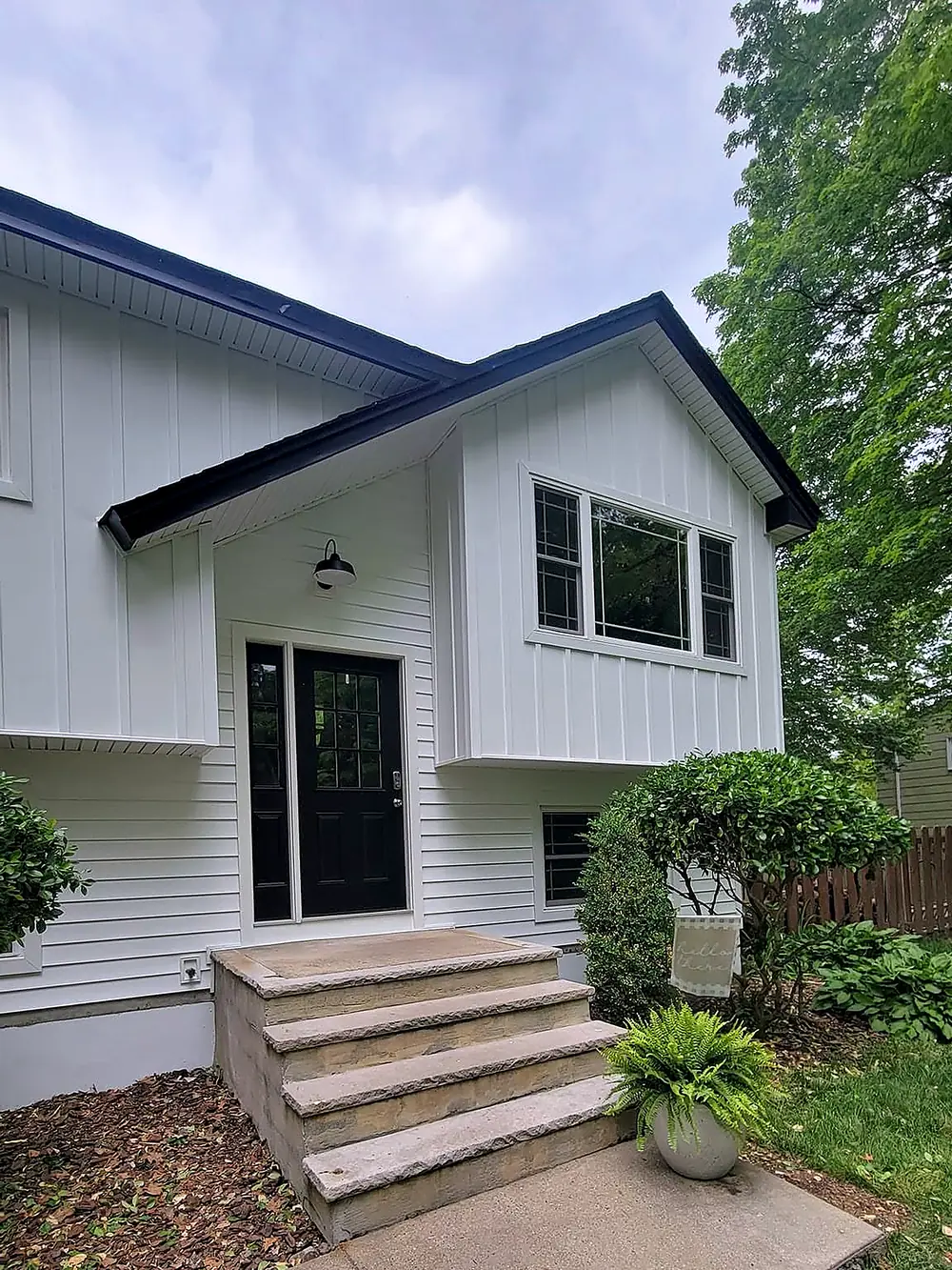 White board and batten siding with black trim and a black entry door