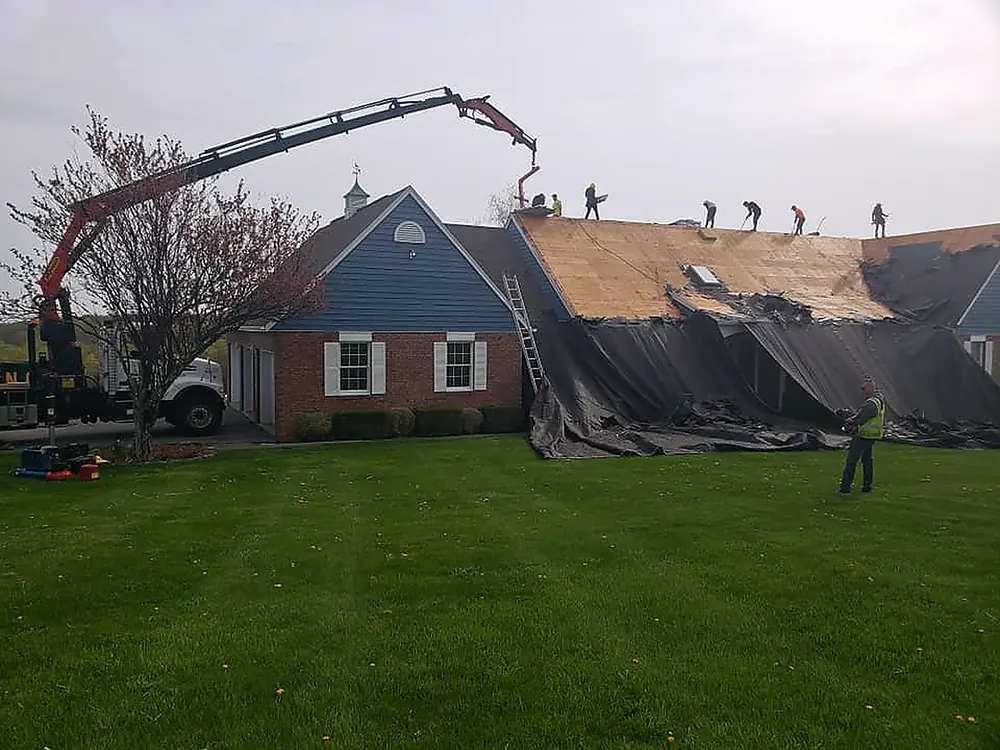 Boom truck lifting shingles to the crew on a full roof replacement