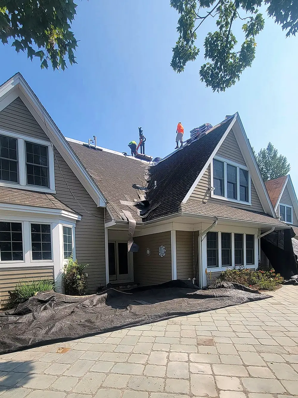 RJ crew mid tear-off with tarps protecting the paver driveway