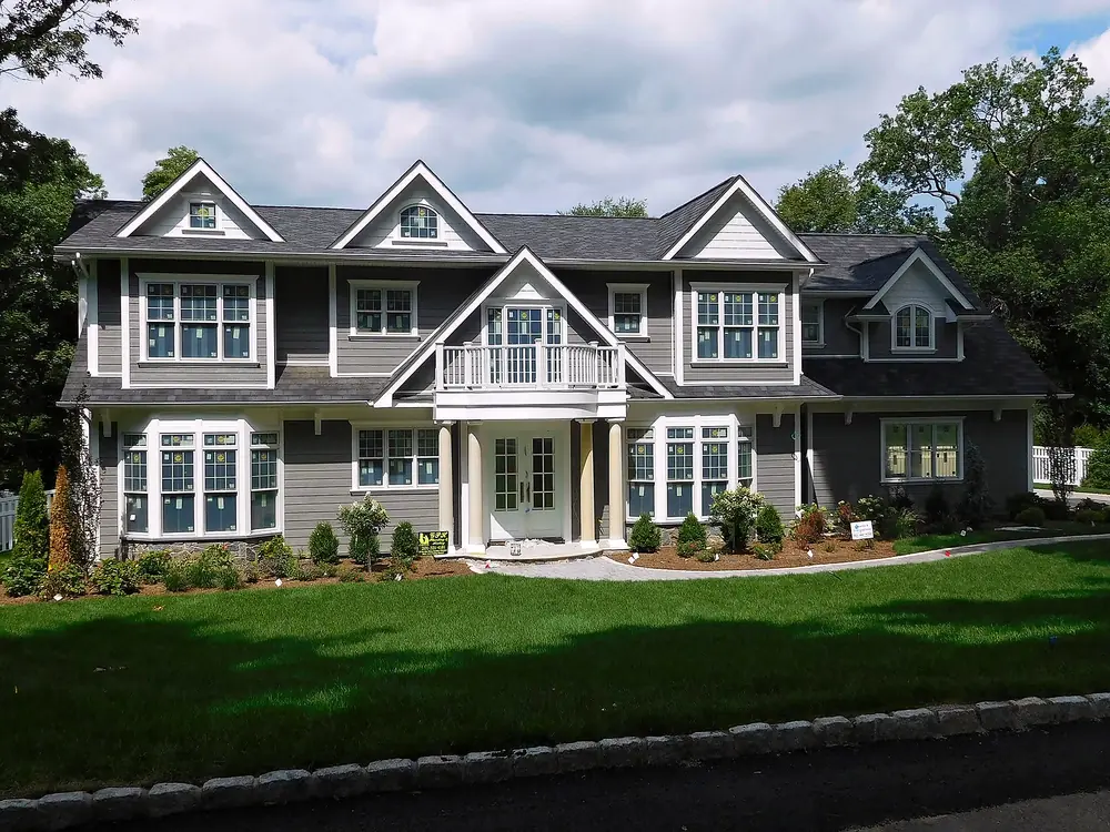 Gray shingle-style colonial with a new roof and white trim