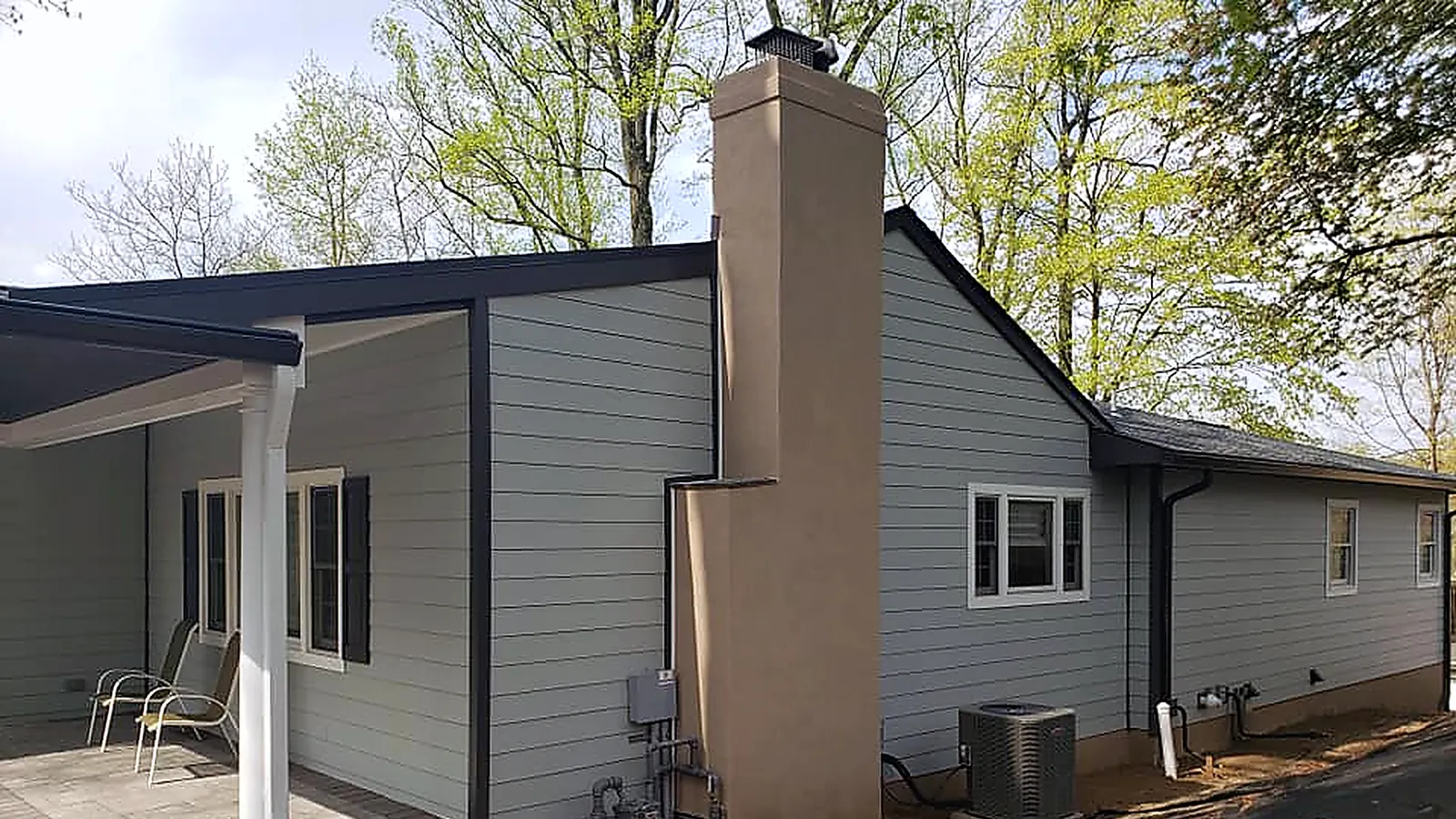 Gray-sided ranch house with a new dark shingle roof, white trim and a new white downspout