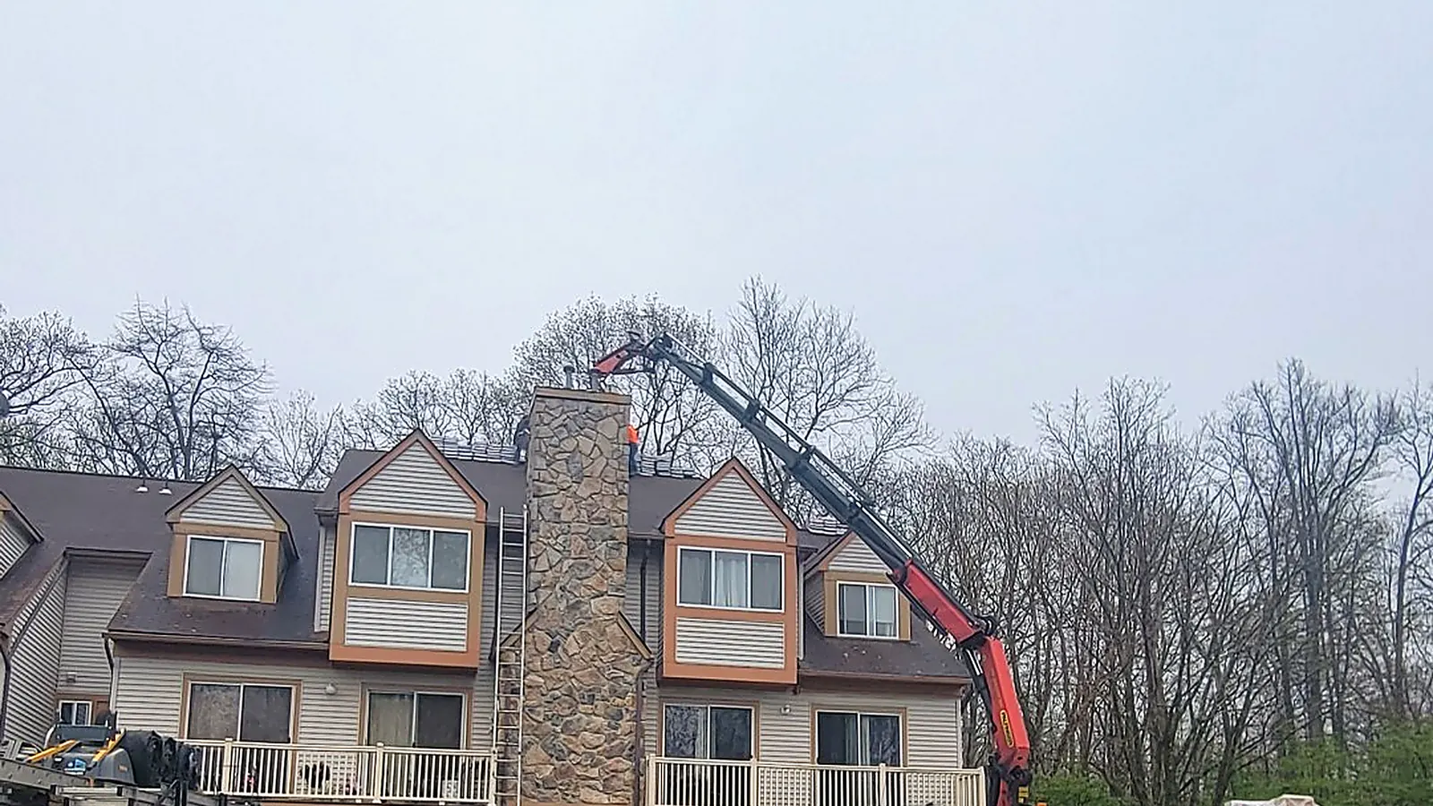 Boom truck lifting shingles onto a townhouse complex roof