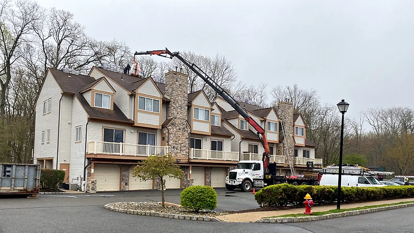 Multi-unit residential buildings with a boom truck and crane setting roofing materials