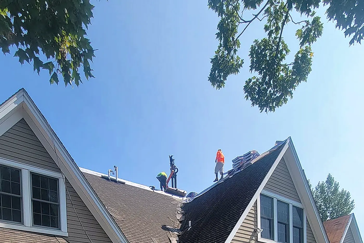 RJ Construction crew tearing off an old roof on a tan house
